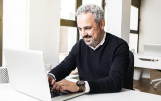 Mann arbeitet an einem Laptop.