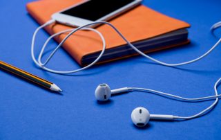 Handy mit Kopfhörern und einem Notizbuch.