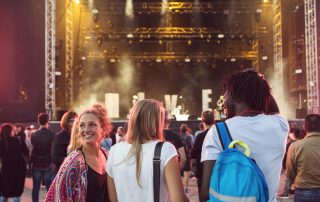 Drei Personen stehen vor einer Bühne.