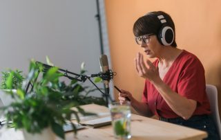 Eine Frau sitzt an einem Tisch und nimmt einen Podcast auf.