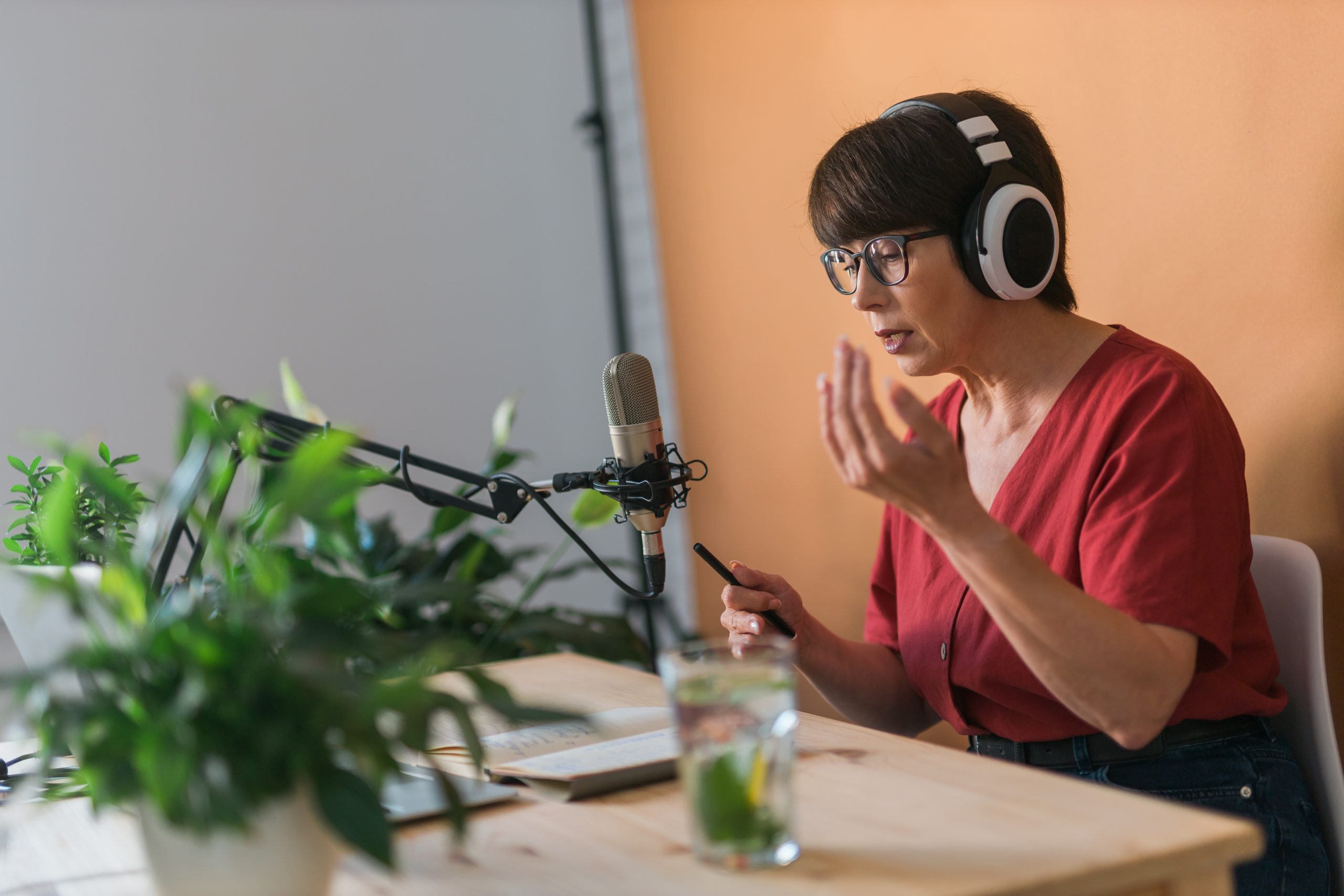 Eine Frau sitzt an einem Tisch und nimmt einen Podcast auf.