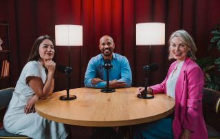 Drei Personen sitzen in einem Aufnahmestudio.