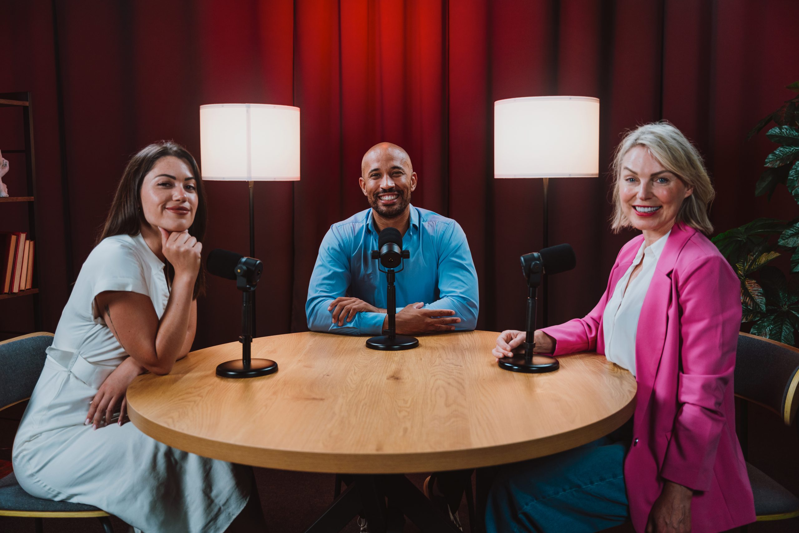 Drei Personen sitzen in einem Aufnahmestudio.