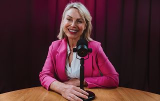 Frau sitzt vor einem Podcastmikrofon.